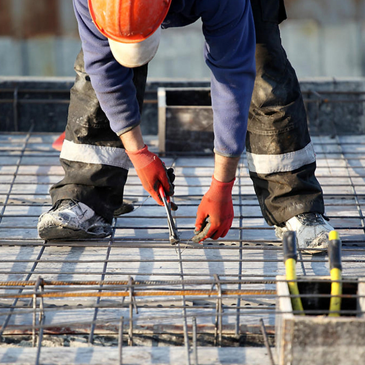 Profissional utilizando arame recozido trançado Tradestar 1,24mm para construção, mostrando a aplicação do produto em amarração de estruturas de aço, ideal para projetos de construção e reparos.