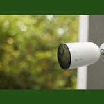 Câmera Externa Bateria EZVIZ CS-CB3 1080P H265 instalada em parede, com design à prova de intempéries, ideal para segurança residencial. Apresenta visão noturna colorida, detecção de movimento humano e integração com assistentes virtuais.