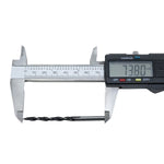 Broca para madeira Tradestar 4x75mm sendo medida com paquímetro digital, mostrando o comprimento de 73.80mm. Ferramenta de aço carbono com 3 pontas, ideal para perfurações precisas em madeira. Kit com 100 unidades.