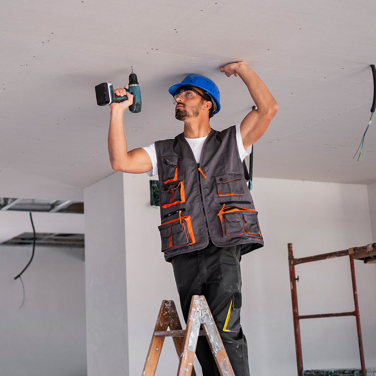 Profissional instalando drywall com parafusadeira, utilizando Parafuso Ponta Broca Flangeado 4,2x13 Tradestar para fixação no teto, em obra.