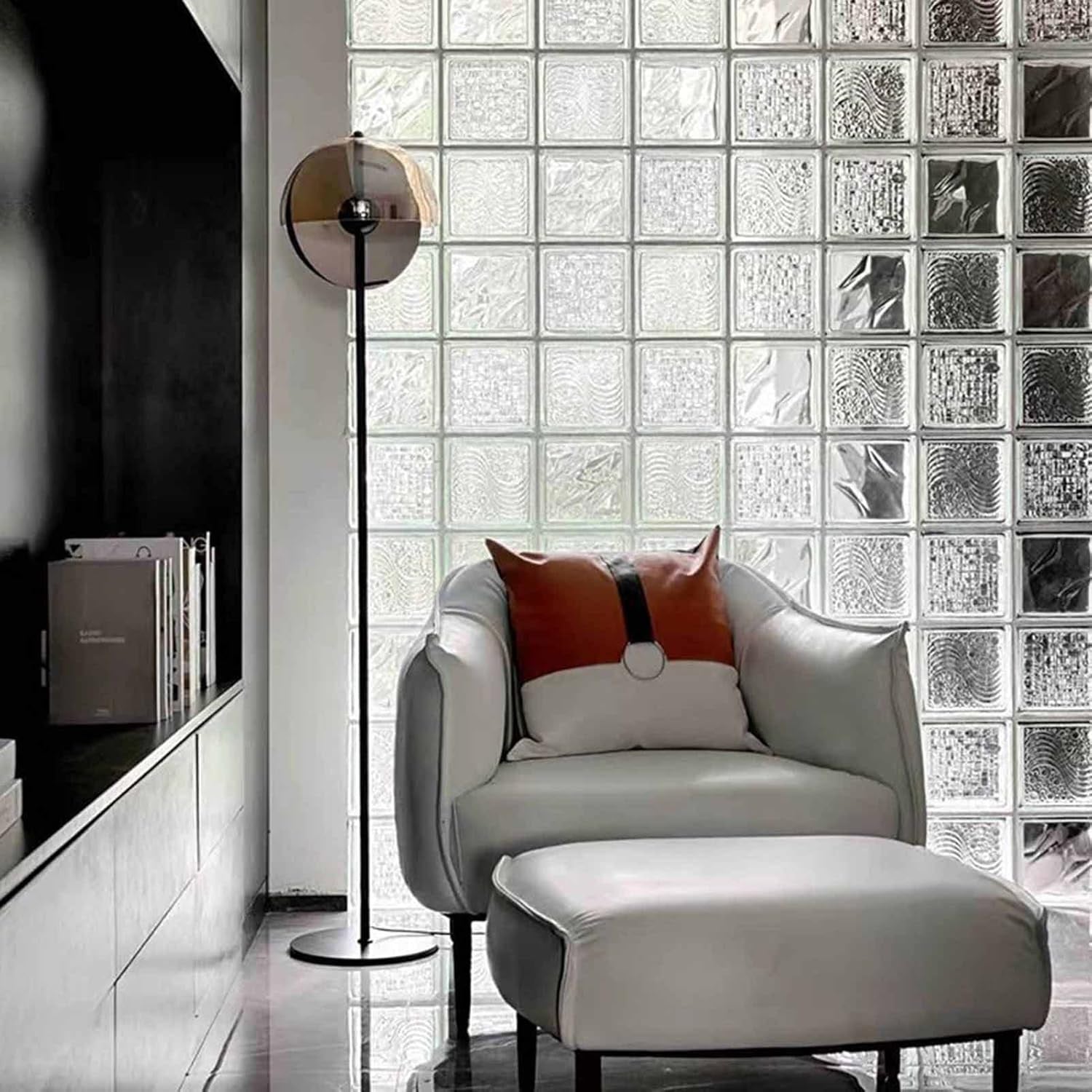 Kit 12 Tijolos Bloco De Vidro Raio Crystal 19x19x8 Tradestar em ambiente moderno, com parede de blocos de vidro, poltrona e luminária. Ideal para divisórias e iluminação natural em casas e escritórios.